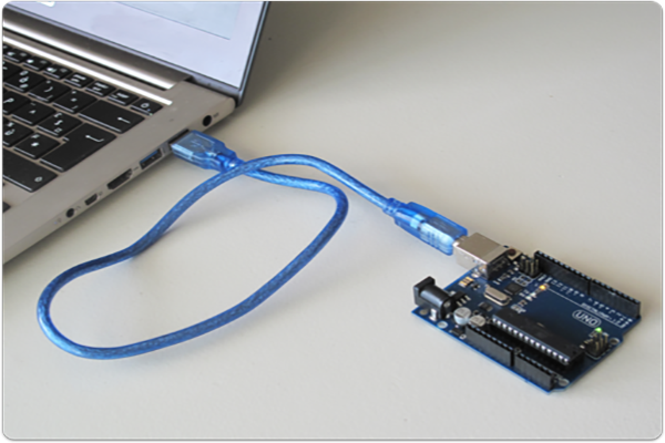 Picture of an Arduino board connected to a computer via USB