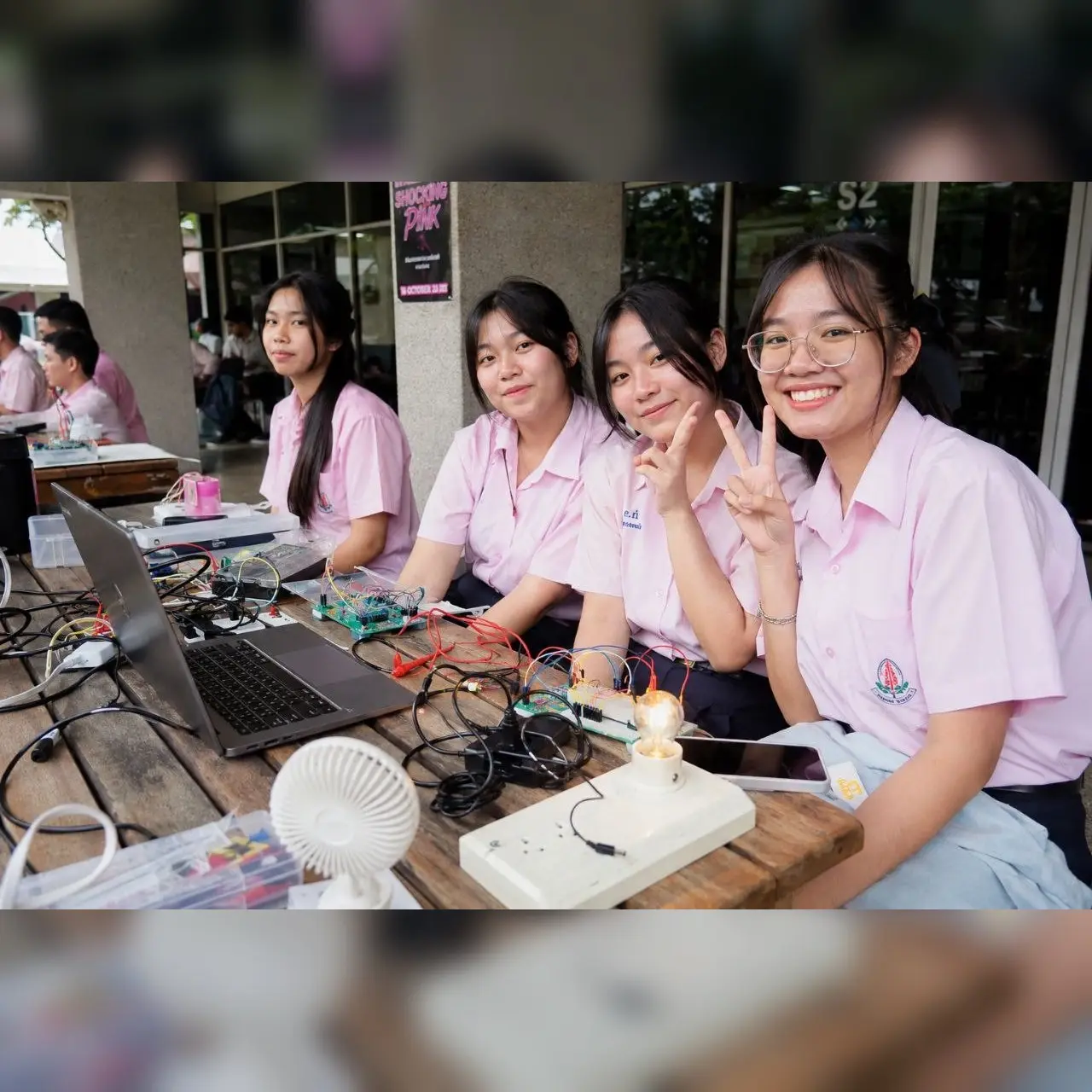ทีมผู้เรียนทำโปรเจคอิเล็กทรอนิกส์บนโต๊ะพร้อม laptop วงจร และพัดลมทดลอง